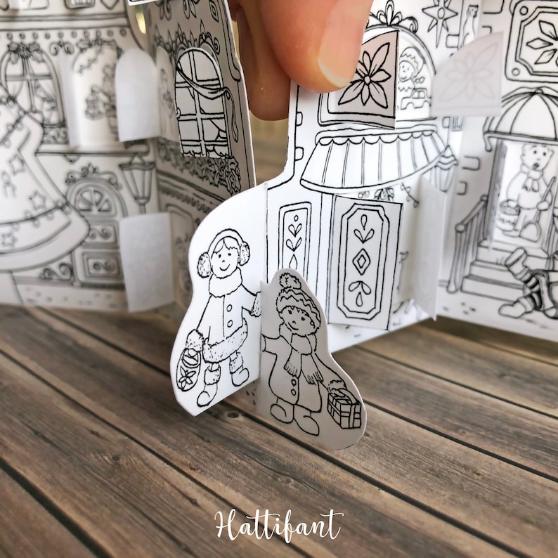 May include: Black and white illustration of a Christmas village scene with two children wearing winter clothes and carrying gifts. The illustration is part of a pop-up book.