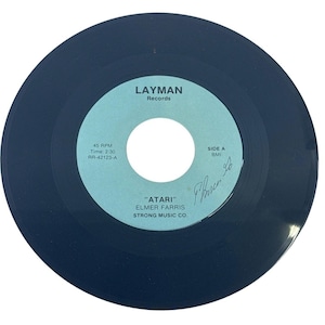 May include: A black 45 RPM vinyl record with a light blue center label. The label features the text LAYMAN Records, SIDE A, BMI, 45 RPM, Time: 2:30, RR-42123-A, ATARI, ELMER FARRIS, and STRONG MUSIC CO. A handwritten signature is visible on the label.