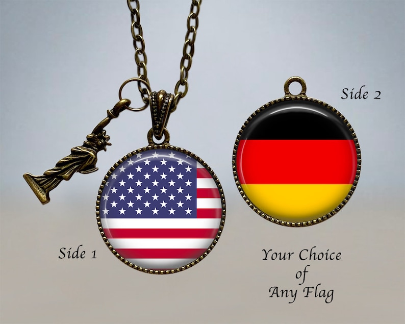 Op de afbeelding: Een ketting met een omkeerbare hanger met aan de ene kant de Amerikaanse vlag en aan de andere kant de Duitse vlag. De hanger is bevestigd aan een bronzen ketting met een klein Vrijheidsbeeld-bedeltje. "Zijde 1" en "Zijde 2" staan op de afbeelding, samen met "Uw keuze van elke vlag".