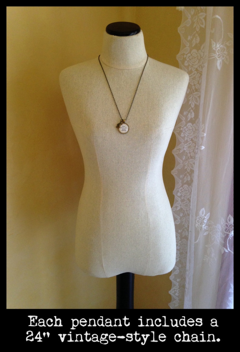 May include: A round pendant necklace with a vintage-style chain. The pendant is made of metal and has a white background with black text that reads "And never will I stop believing in you".