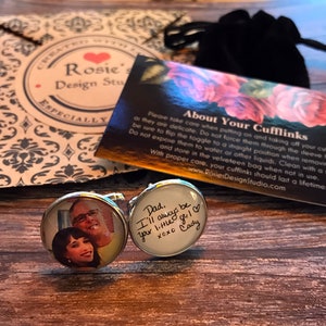 May include: A pair of silver cufflinks with a photo of a couple on one cufflink and a handwritten message on the other cufflink. The message reads "Dad. I'll always be your little girl XOXO Cady".