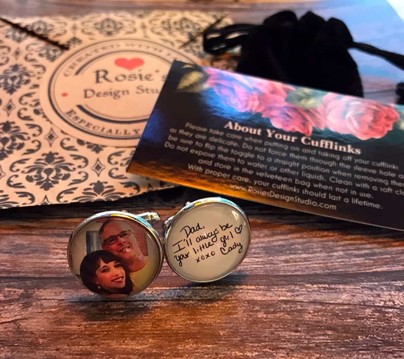 May include: A pair of silver cufflinks with a photo of a couple on one cufflink and a handwritten message on the other cufflink. The message reads "Dad. I'll always be your little girl XOXO Cady".