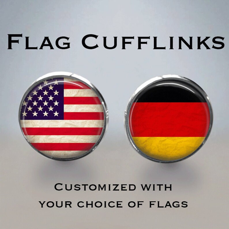 Op de afbeelding: Een paar manchetknopen met de Amerikaanse en Duitse vlag. De manchetknopen zijn rond en hebben een zilveren afwerking. "FLAG CUFFLINKS" en "CUSTOMIZED WITH YOUR CHOICE OF FLAGS" staan in zwarte tekst op een grijze achtergrond.