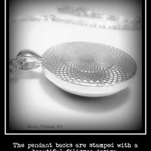 May include: Close-up of the back of a silver pendant with a filigree design. The pendant is attached to a silver chain.