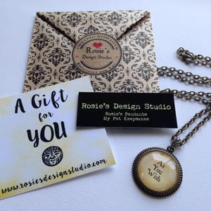 May include: A gift tag with the text "A Gift for You" and a website address. A brown paper envelope with a black and white pattern and a sticker that says "Rosie's Design Studio". A necklace with a round pendant that says "As You Wish".