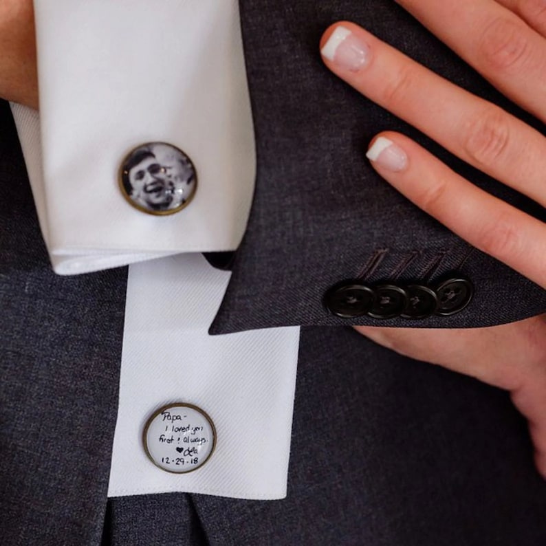 May include: Two round cufflinks with a black and white photo of a man in one and a handwritten message in the other. The message reads "Papa - I loved you first & always.  Love,  12-29-18".