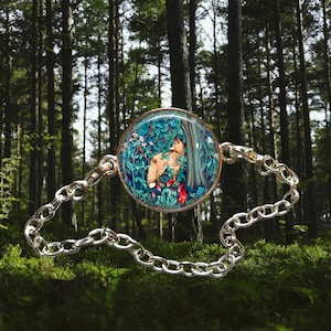May include: A silver chain bracelet with a round glass charm featuring a colorful depiction of a fox in a forest scene.