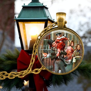 May include: A gold chain necklace with a round glass pendant featuring a vintage illustration of a family walking in the snow. The illustration depicts a man carrying a child on his shoulders, a woman holding a child's hand, and another woman walking behind them. The pendant is surrounded by a gold metal frame.