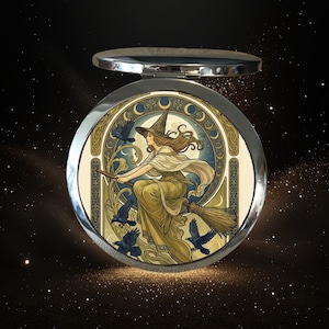 May include: A round silver compact mirror featuring an illustration of a person in a pointed hat riding a broomstick, surrounded by black birds and a moon phase border. The artwork uses muted gold, cream, and blue tones in an art nouveau style.