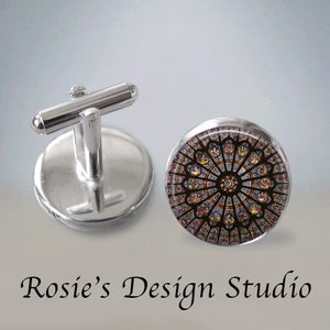 May include: A pair of silver cufflinks with a round glass insert featuring a colorful stained glass window design.