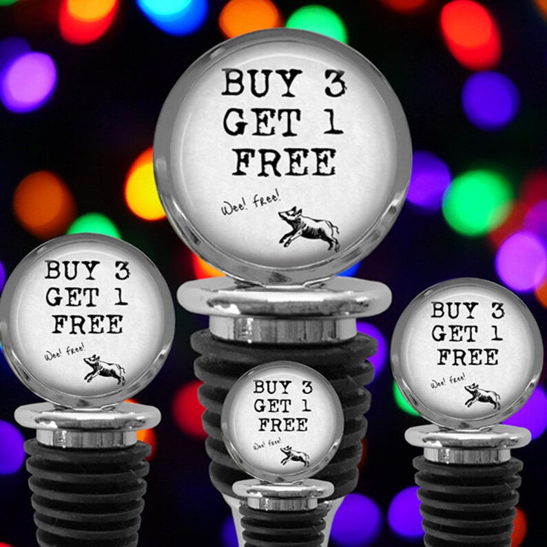May include: Four silver-toned bottle stoppers with black rubber ribbed bases. Each circular top features the black text "BUY 3 GET 1 FREE" and "Wee! free!" above a small black illustration of a running pig, set against a white background.