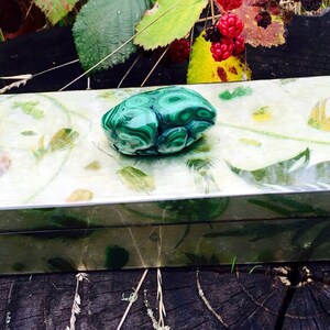 May include: A green malachite stone box with a floral design. The box is closed and has a green malachite stone knob.