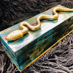 May include: A blue and gold decorative box with a snake design. The box is made of wood and has a mosaic pattern.