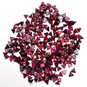 May include: A large quantity of small, triangular, red gemstone cabochons. The cabochons are faceted and have a glossy finish.