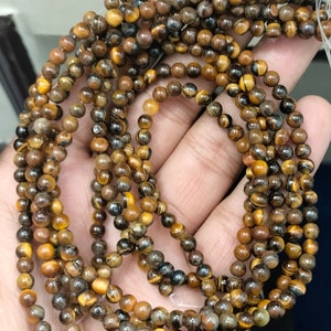 May include: A strand of round, brown and gold tiger's eye beads. The beads have a natural, polished finish.