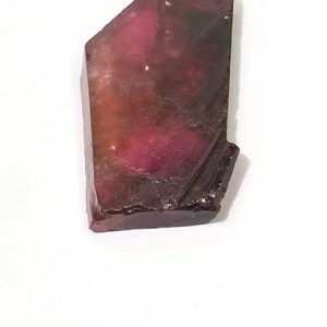 May include: A large, rough, pink and brown crystal with a pointed tip.