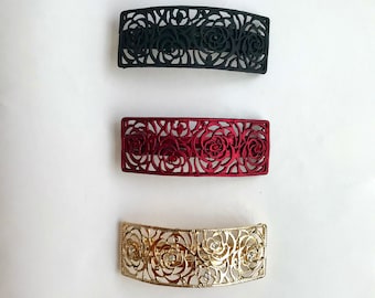 Diseño de rosa: clip de metal curvo mediano en color dorado, negro y rojo adornado con cristales