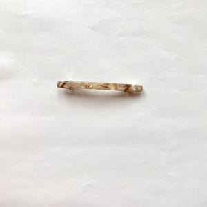 May include: A brown and white marbled hair clip.