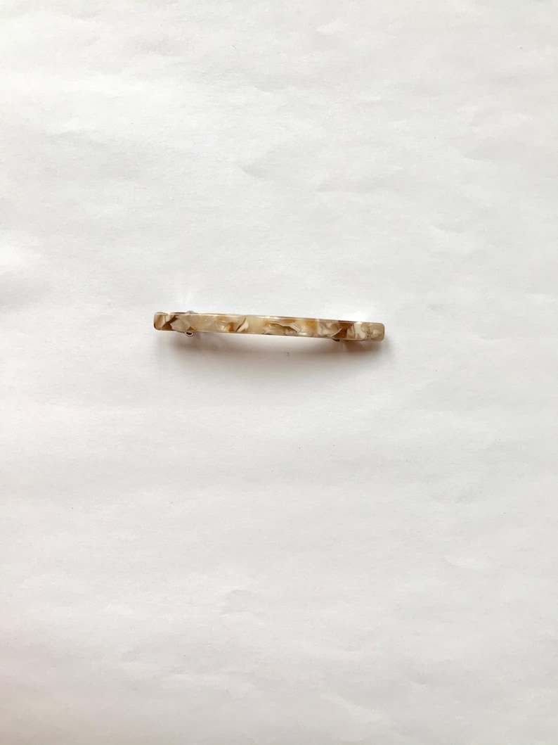 May include: A brown and white marbled hair clip.