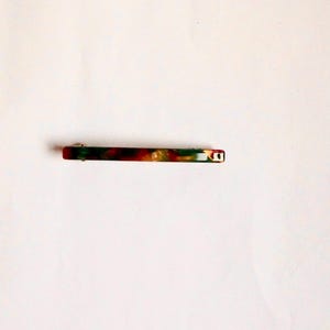 May include: A green, red, and gold marbled plastic hair clip.