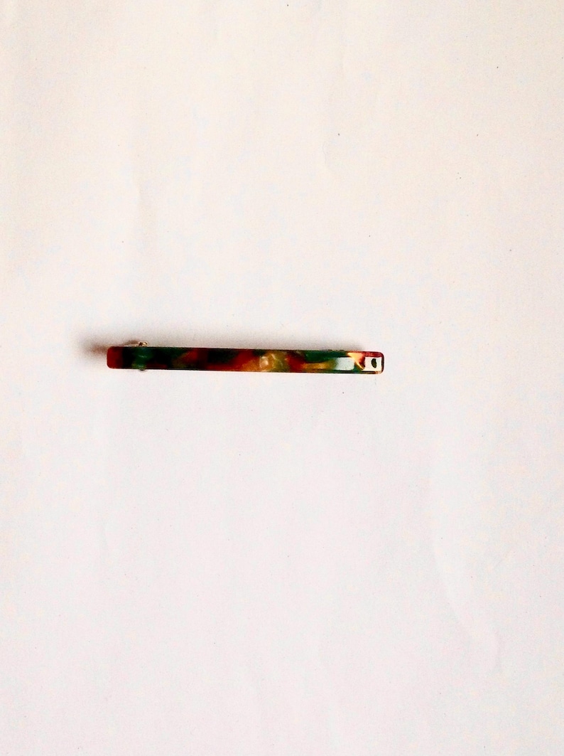 May include: A green, red, and gold marbled plastic hair clip.