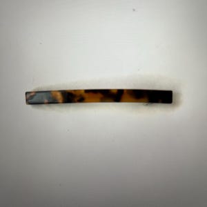 May include: A brown and black tortoiseshell hair clip.
