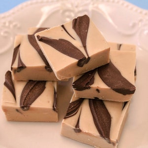 May include: A close-up of a plate of homemade fudge with swirls of brown and white. The fudge is cut into squares and stacked on top of each other.