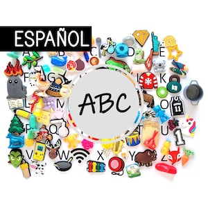 Puede incluir: Una colección de coloridos dijes para zapatos con varios diseños, incluyendo un diamante, un koala, un suéter navideño y un unicornio. La palabra "ESPAÑOL" se muestra en un rectángulo negro, y las letras "ABC" en un círculo blanco.