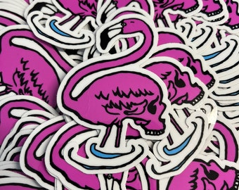 May include: A stack of pink flamingo stickers with a skull design. The flamingos are outlined in black and have blue water underneath them.