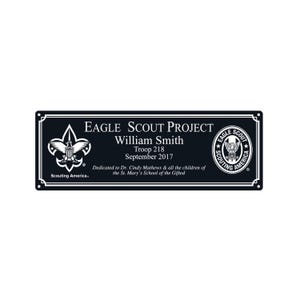 May include: Black rectangular plaque with white border and text. The text reads "EAGLE SCOUT PROJECT, William Smith, Troop 218, September 2017." Includes the Eagle Scout logo and "Scouting America" text.