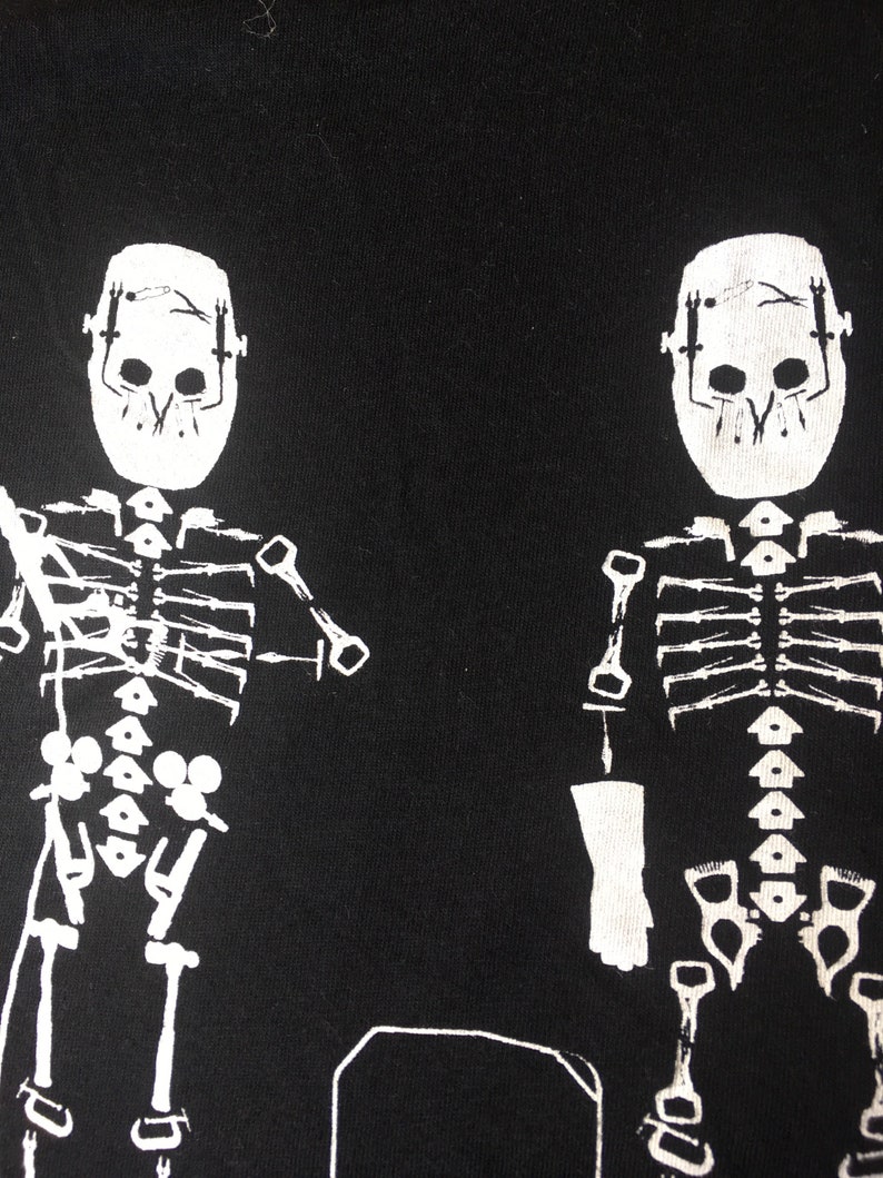May include: Two white skeleton figures with masks on a black background. The skeletons are wearing a mask over their skulls and have a rib cage and bones visible.