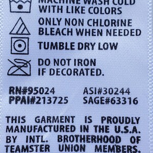 Peut inclure: Une &eacute;tiquette de tissu blanche avec du texte noir indiquant les instructions d'entretien des v&ecirc;tements. L'&eacute;tiquette comprend des symboles de lavage, tels que lavage en machine &agrave; froid, s&eacute;chage en machine &agrave; basse temp&eacute;rature et ne pas repasser si d&eacute;cor&eacute;. Fabriqu&eacute; aux &Eacute;tats-Unis.