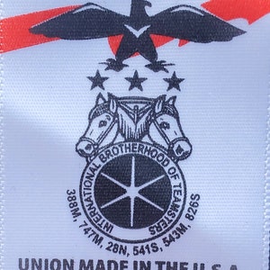May include: A white tag with a red, white and blue American flag design. The tag says "UNION MADE" in black text. Below the flag is a black and white logo with a circle and five stars. The logo says "INTERNATIONAL BROTHERHOOD OF TEAMS" and has numbers around the circle. Below the logo is the text "UNION MADE IN THE U.S.A. 100% COTTON X-LARGE" in black text.
