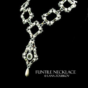 May include: A white beaded necklace with a geometric design. The necklace features a large, teardrop-shaped pendant with a clear crystal in the center. The pendant is attached to the necklace with a chain of white beads. The necklace is called "Funtile Necklace" and is by Lana Zoubov.