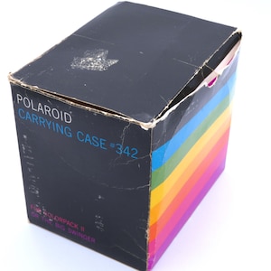 May include: Vintage Polaroid Carrying Case #342, a black box with a rainbow-striped side. The box is designed for Colorpack 8 or The Big Swinger cameras. The box shows signs of wear and tear.