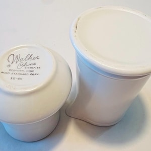 May include: Two white ceramic cups, one with a lid. The bottom of the cup has the text "Walker China Vitrified Bedford, Ohio ALCO Standard Corp. 12-49".