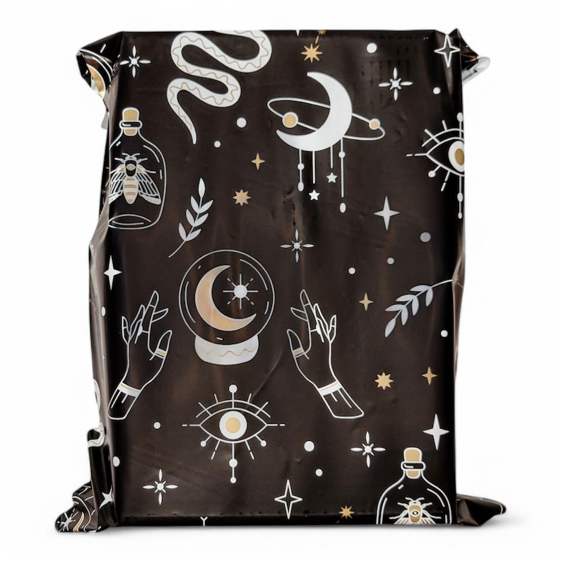 May include: Black and gold patterned fabric with a repeating design of stars, moons, eyes, snakes, hands, and bottles. The fabric has a shiny, metallic finish.