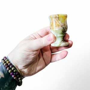 May include: A small, green and brown, marble goblet with a wide base.