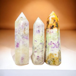 May include: Three crystal points with a white, green, and yellow base. The crystals have purple and pink inclusions.