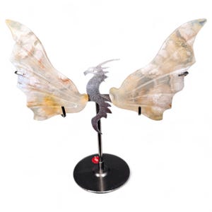 May include: A decorative dragon sculpture with agate wings. The wings are a mix of beige, white, and orange hues. The dragon is made of silver metal and is mounted on a silver base.