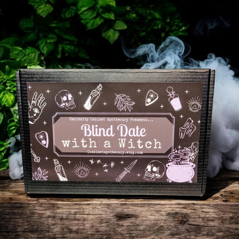 May include: A brown cardboard box with a black and white label that says "Curiosity Cabinet Apothecary Presents... Blind Date with a Witch" and features various witchy illustrations.