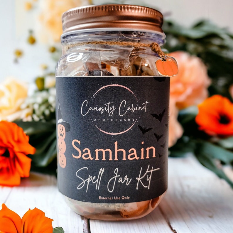 May include: A glass jar with a black label that says "Curiosity Cabinet Apothecary" and "Samhain Spell Jar Kit". The jar is filled with herbs and other ingredients. The label also says "External Use Only".