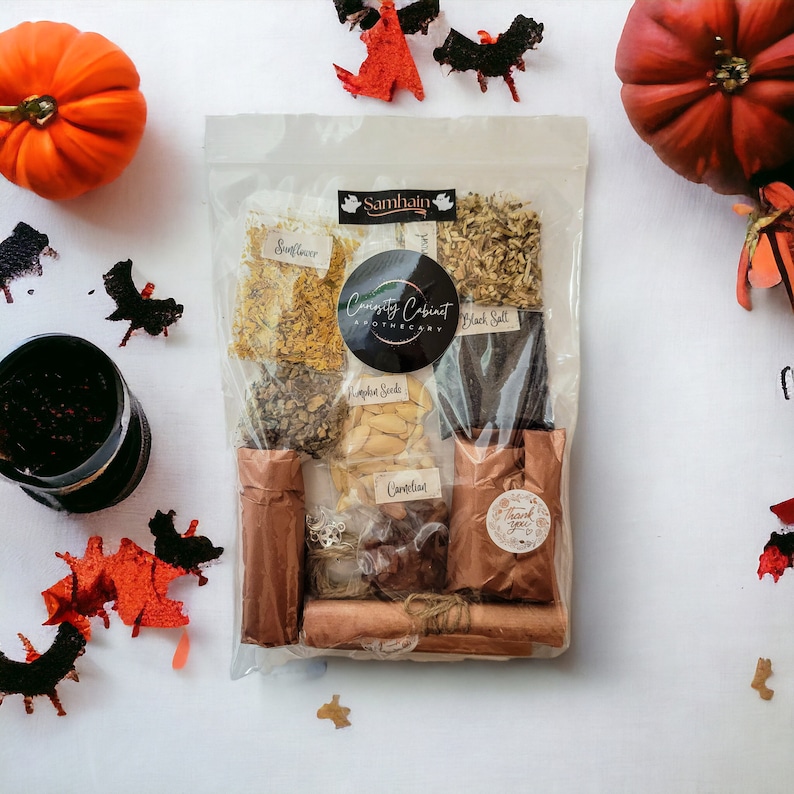 May include: A clear plastic bag filled with various herbs and spices for a Samhain ritual. The bag includes sunflower, apple seeds, black salt, carline thistle, and a small brown paper bag labeled "Thank you". The bag is labeled "Samhain" and "Curiosity Cabinet Apothecary".