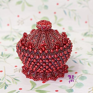 May include: A small, red beaded trinket box with a decorative lid. The box is made of tiny, round beads and has a delicate, intricate design.