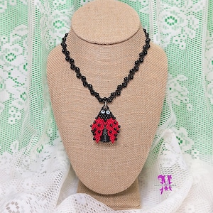 May include: A black beaded necklace with a ladybug pendant. The ladybug is red with black spots and has white eyes.