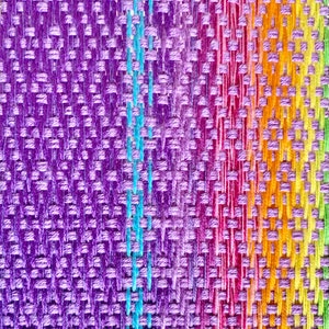 May include: A close-up of a woven fabric with a rainbow pattern. The fabric is made of different colored threads that are woven together to create a colorful design.