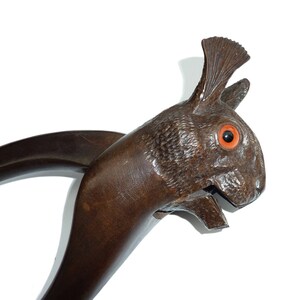 Pode incluir: Um quebra-nozes de madeira em forma de coelho com um rosto esculpido e olhos de vidro vermelho.