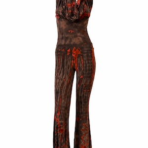 May include: A sleeveless jumpsuit featuring a cowl neckline and flared pant legs. The garment is colored in a dark brown and vibrant orange tie-dye pattern that creates a vertical, streaked effect across the entire length of the piece.