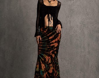 Peut inclure: Une jupe longue jusqu'au sol avec un motif tie-dye noir, orange et bleu sarcelle, associée à un haut noir à manches longues doté d'une encolure carrée et d'une fermeture à nouer sur le devant, portée avec des chaussures à plateforme noires.