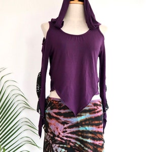 Peut inclure: Un haut à capuche violet avec des épaules dénudées et une jupe tie-dye. Le haut a des manches longues avec des détails en dentelle noire. La jupe est un mélange vibrant de bleu, de violet et de noir.